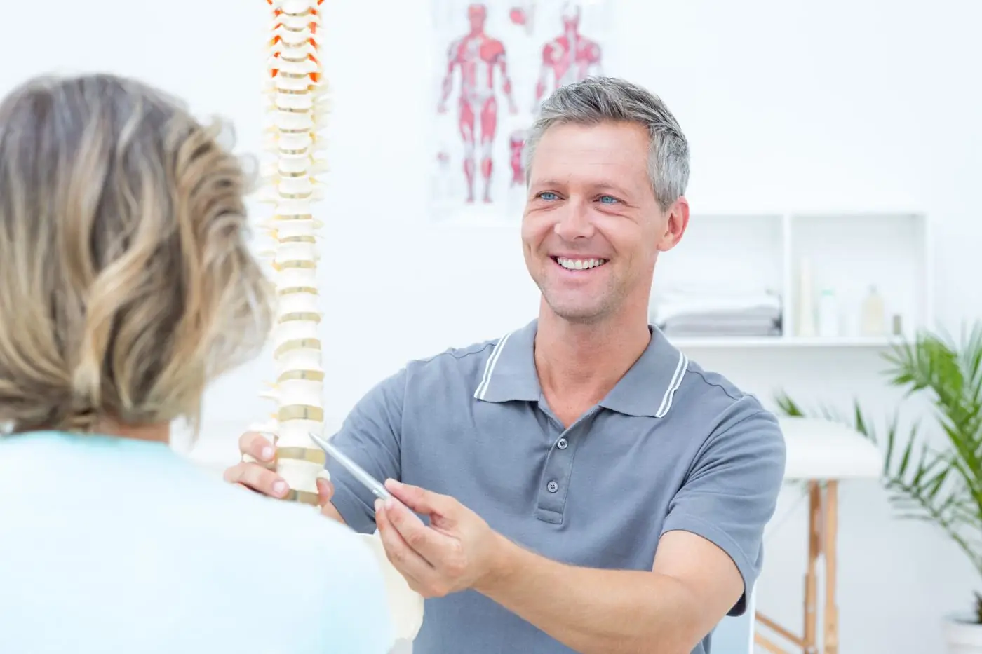 Physiotherapist explaining back pain using a spine model